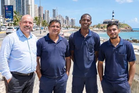 Equipe da Refrigeração Natal na orla de Natal — técnicos e administração com o Farol e a cidade ao fundo
